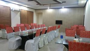 una sala de conferencias con mesa de cristal y sillas rojas en The First Hotel, en Multán
