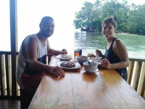un homme et une femme assis à une table avec de la nourriture dans l'établissement Nusa Nalan Beach Resort, à Rumah Olat