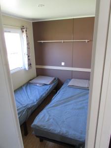 een kleine kamer met 2 bedden en een raam bij Mobil Home 3 ch in Saint-Georges-de-Didonne