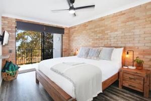 a bedroom with a large bed and a brick wall at Illawong Apartment 7 in Mooloolaba