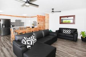 a living room with a black couch and a kitchen at Illawong Apartment 7 in Mooloolaba