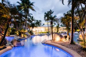 uma piscina com palmeiras e um resort em Reef Resort Villas Port Douglas em Port Douglas