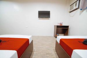 two beds in a room with a tv on the wall at RedDoorz at Traveler's Inn Bajada Davao in Davao City