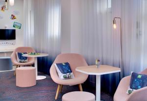 ヴィシーにあるHôtel ibis Styles Vichy Centreのテーブル2台と椅子、テーブル1台とテーブル2台と椅子1脚が備わる客室です。