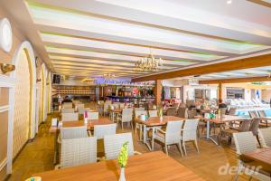 a restaurant with wooden tables and white chairs at Lavinia Apart & Hotel in Alanya