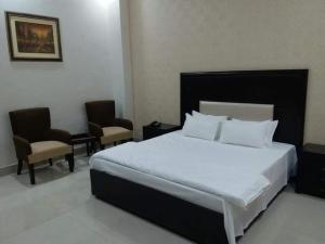 ShekhūpuraにあるSultan Grand Hotelのベッドルーム1室(大型ベッド1台、椅子2脚付)