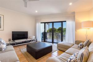 a living room with a couch and a tv at Wake up to ocean views in stylish comfort in Sunshine Beach