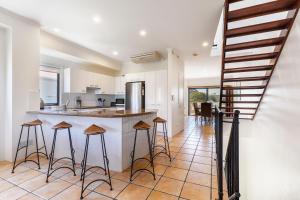 a kitchen with a counter and stools in a room at Wake up to ocean views in stylish comfort in Sunshine Beach