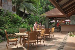 un hombre de pie en una mesa con sillas en un patio en El Galleon Beach Resort en Puerto Galera