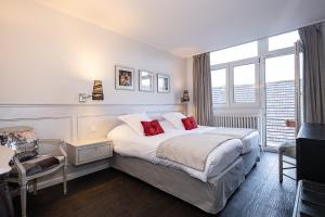 a bedroom with a large bed with red pillows at The Originals City Hotel de l Ange Guebwiller in Guebwiller