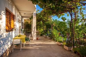 a patio with a yellow table and chairs at Apartments Marilka in Podgora