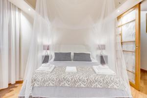 a white bedroom with a bed with a mosquito net at VENETO COMFORTABLE Apartment in Rome