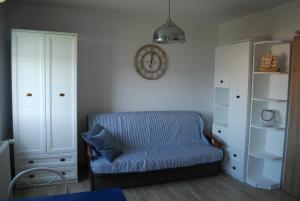 a blue couch in a room with a clock on the wall at Apartament Morski in Hel