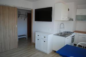 a white kitchen with a sink and a stove at Apartament Morski in Hel