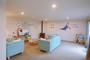 a living room with blue furniture and a dolphin on the wall at The Ocean Dream in Rotorua