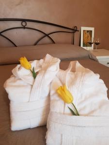 - deux serviettes sur un lit avec deux fleurs jaunes dans l'établissement Il Giardino di Tolù Siracusa, à Città Giardino