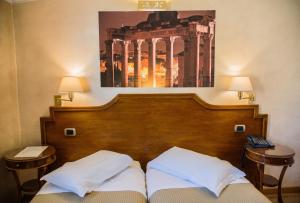 a bed with two pillows and a picture on the wall at Hotel Kent in Rome