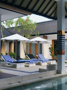 a patio with chairs and umbrellas next to a pool at Villa Casablanca Surf Keramas in Keramas