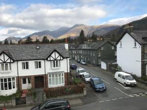 a town with cars parked on a street with mountains at Winchester House in Keswick