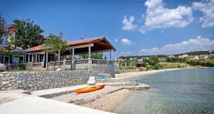 een huis met een kajak op het strand naast het water bij Guesthouse Dupin in Vlašići