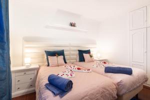 two beds in a bedroom with blue pillows on them at Casa Lira in Arco da Calheta