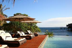 einen Pool mit Stühlen und Sonnenschirmen am Meer in der Unterkunft Cauayan Island Resort and Spa in El Nido