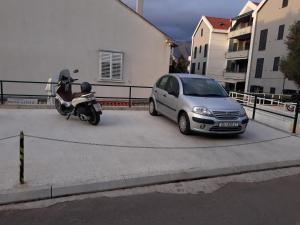 a car and a scooter parked in a parking lot at Rooms Kvestic in Dubrovnik