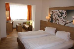 ポイスドルフにあるWeinhotel Riederのベッドとソファ付きのホテルルーム