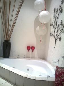 a bath tub in a bathroom with two red wine glasses at Khokha Moya Guesthouse in Ermelo