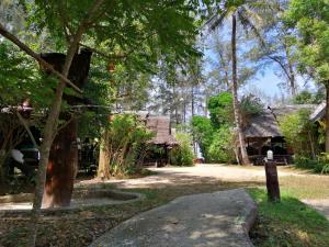 a path in front of a house with trees at Fisherman's Hut , ขนำชาวเลโฮมสเตย์ in Pak Meng