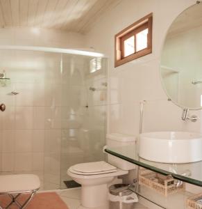 y baño con aseo, lavabo y espejo. en Chalé dos Coelhos en Porto Seguro