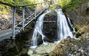 ein Wasserfall auf einem Berg mit einer Brücke daneben in der Unterkunft Apartmán Katka in Sučany