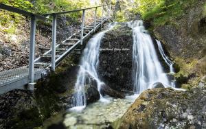 a waterfall on a mountain with a bridge next to it at Apartman u Mareka in Sučany