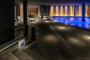 a swimming pool in a building with blue water at Gran Hotel Rey Don Jaime in Castelldefels