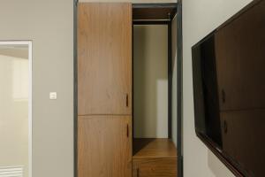 a closet with a tv and a wooden cabinet at RedDoorz near Puri Indah Mall in Jakarta