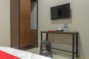 une chambre avec un lit et un bureau avec une télévision dans l'établissement RedDoorz near Puri Indah Mall, à Jakarta 10 autres photos