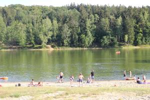 un grupo de personas en una playa cerca de un lago en Domki nad jeziorem w Karłowicach, en Karłowice