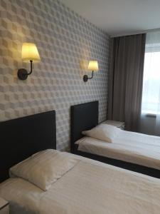 a hotel room with two beds and two lamps on the wall at Dzintarjura in Ventspils