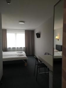 ein Hotelzimmer mit 2 Betten, einem Tisch und einem Stuhl in der Unterkunft Dzintarjura in Ventspils