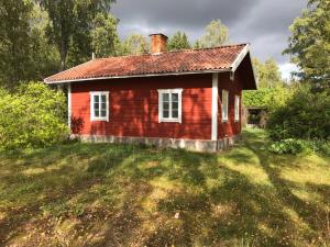 a small red house on a grass field at Oxelbacka cottage in Enköping