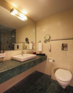 W łazience znajduje się umywalka, toaleta i lustro. w obiekcie Red Fox Hotel, Alwar w mieście Alwar