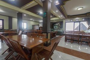 une salle à manger avec des tables et des chaises en bois dans l'établissement RedDoorz Syariah @ Cipanas, à Sindanglaya