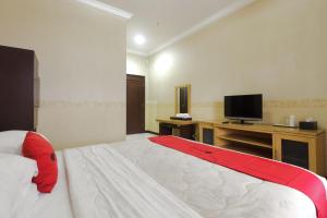 - une chambre avec un grand lit et une télévision dans l'établissement RedDoorz Syariah @ Cipanas, à Sindanglaya