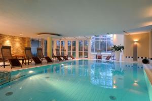 a large swimming pool with chairs and a table at Hotel Caroline Mathilde in Celle