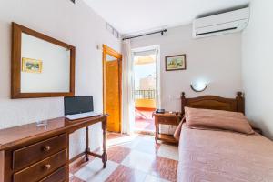 a bedroom with a bed and a desk with a laptop at Hotel Sevilla in Almería