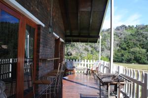 eine Veranda eines Hauses mit Stühlen und Tischen in der Unterkunft Salt River Lodge in Knysna