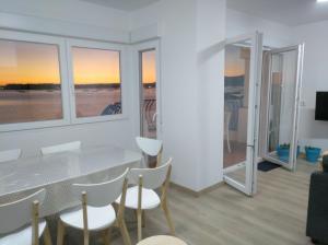 uma sala de jantar com mesa, cadeiras e janelas em Apartamentos Poniente em Vilanova de Arousa