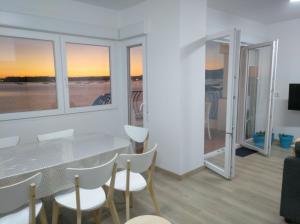 a dining room with a table and chairs and windows at Apartamentos Poniente CON y SIN TERRAZA in Villanueva de Arosa
