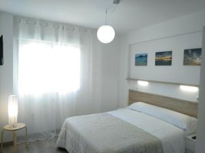 a white bedroom with a bed and a window at Apartamentos Poniente CON y SIN TERRAZA in Villanueva de Arosa