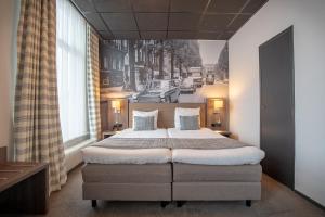 a bedroom with a large bed and a painting on the wall at Hotel Cornelisz in Amsterdam